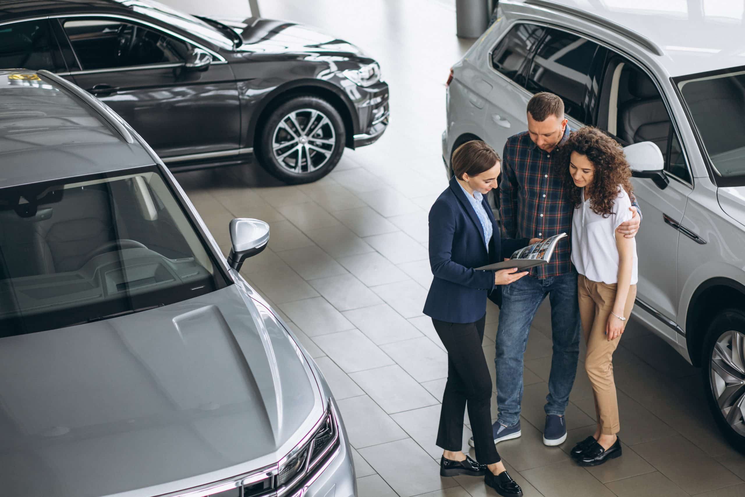 young couple talking sales person car showroom
